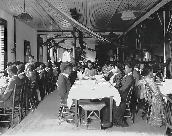 Interior view of dining hall, decorated for the holidays, with students... Tuskegee Institute, c1902 Creator: Frances Benjamin Johnston
