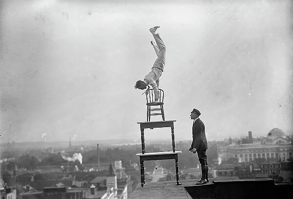 J. Reynolds, Performing Acrobatic And Balancing Acts On High Cornice Above 9th Street, N.W. 1917. Creator: Harris & Ewing. J. Reynolds, Performing Acrobatic And Balancing Acts On High Cornice Above 9th Street, N.W. 1917