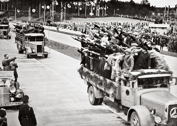Labourers salute Hitler from packed trucks on a Nazi-built road, 1936