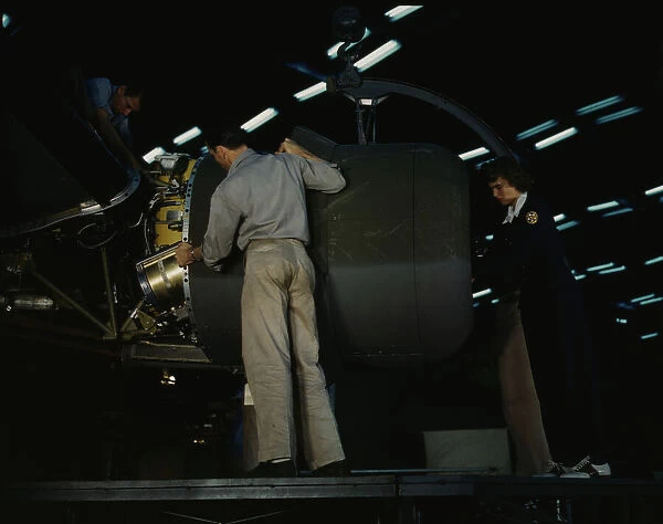 Lowering an engine in place in assembling a C-87... Consolidated Aircraft... Fort Worth, Texas, 1942 Creator: Howard Hollem