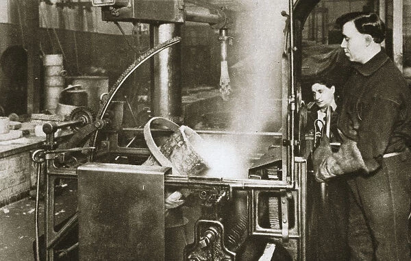 Making money; lowering a pot of liquid metal into a machine, 20th century. Artist