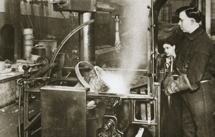 Framed Print : Making money; lowering a pot of liquid metal into a machine, 20th century. Artist Framed Print : Making money; lowering a pot of liquid metal into a machine, 20th century. Artist