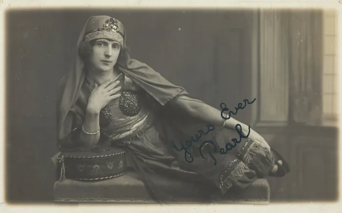 Framed Print : A man in drag, poses wearing delicate attire; curled up on a piece of furniture, [1910-1919?]. Creator: Unknown