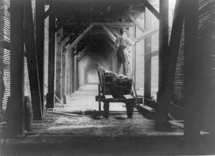 Framed Print : Man standing on boards on cart in sawmill and stacking the boards, Duluth vicinity, Minnesota, 1903. Creator: Frances Benjamin Johnston Framed Print : Man standing on boards on cart in sawmill and stacking the boards, Duluth vicinity, Minnesota, 1903. Creator: Frances Benjamin Johnston