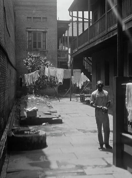 Man standing in a courtyard, New Orleans, between 1920 and 1926. Creator: Arnold Genthe