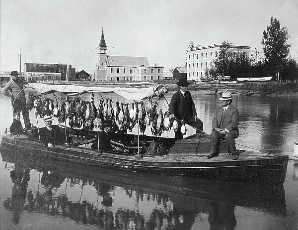 Marshall Erwin in front of a boat containing a kill of ducks, between c1900 and 1927. Creator: Unknown