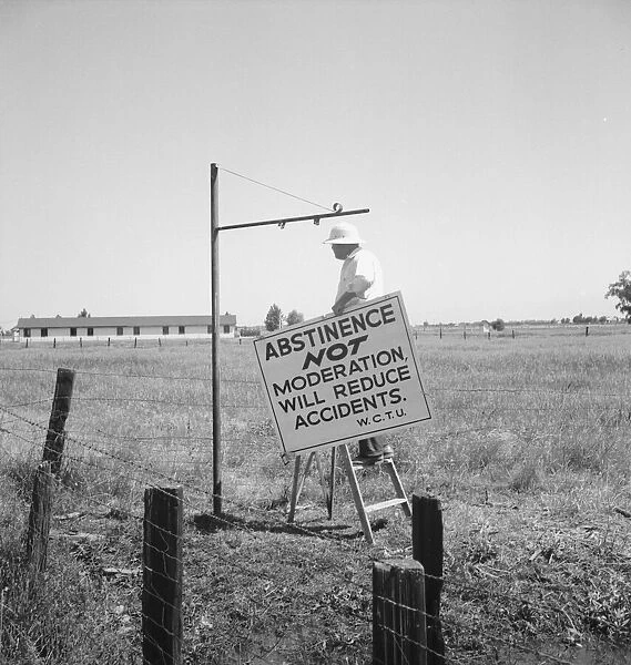 Member of the committee...erects sign on U.S. 99 highway, near Hanford, California, 1939. Creator: Dorothea Lange
