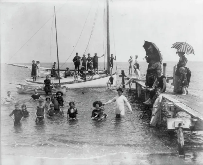 Framed Print : Men, women, and children in bathing suits on dock, sailboats, and in water... c1880. Creator: Unknown Framed Print : Men, women, and children in bathing suits on dock, sailboats, and in water... c1880. Creator: Unknown