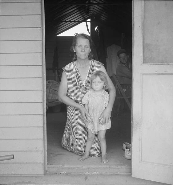 Migrant mother and child at doorway of steel shelter, FSA camp, Tulare County, 1939. Creator: Dorothea Lange