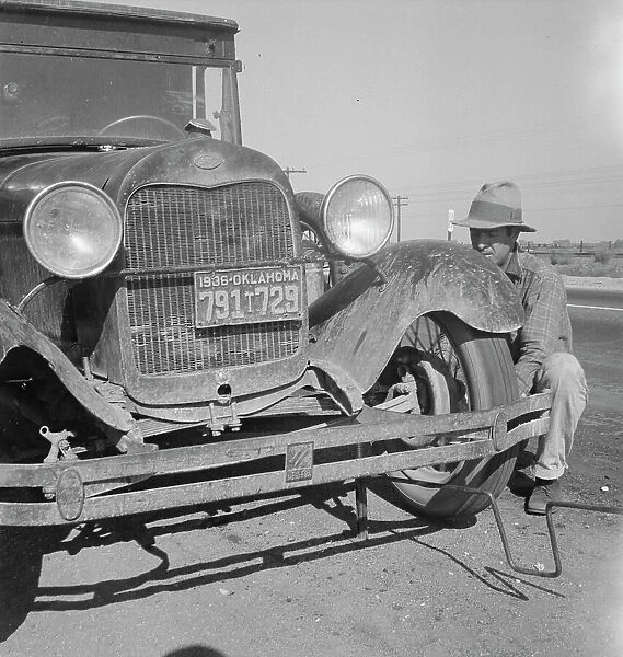 Migrant worker from Oklahoma repairing tire on California highway, 1936. Creator: Dorothea Lange