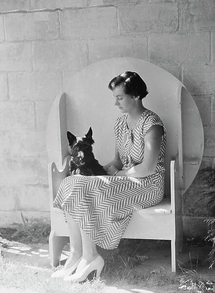 Mrs. Walter Fletcher with dog, seated outdoors, between 1933 and 1942. Creator: Arnold Genthe