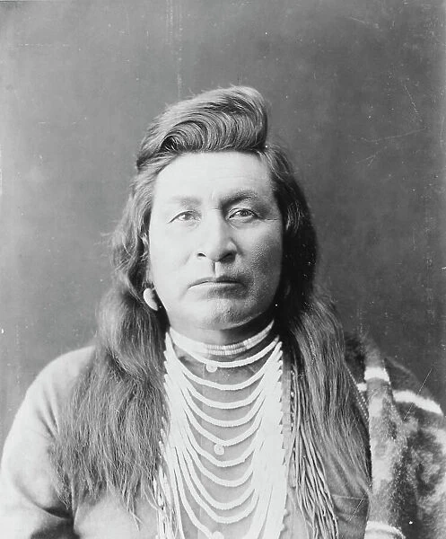 Nez Percé man, head-and-shoulders portrait, facing front, wearing bead necklace... c1899. Creator: Edward Sheriff Curtis
