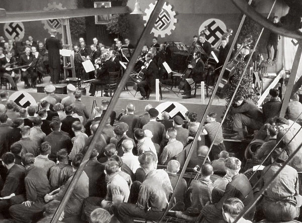 An orchestra plays to some factory workers as they take a break from work, Germany, 1936