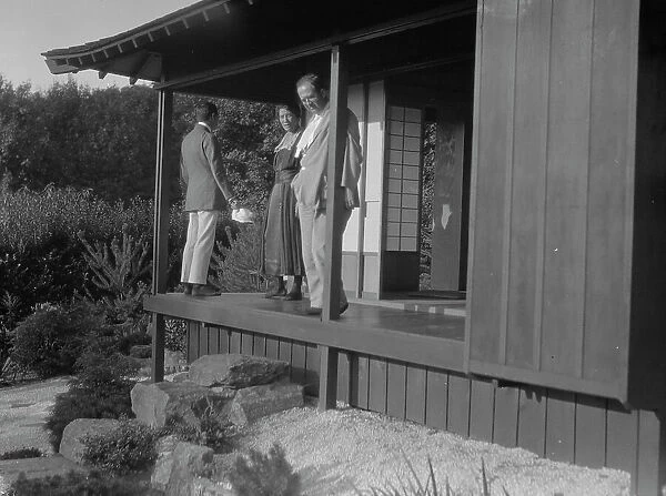 Three people standing on the porch of a Japanese-style building in a garden... A.W. Bahr, c1917-1934 Creator: Arnold Genthe