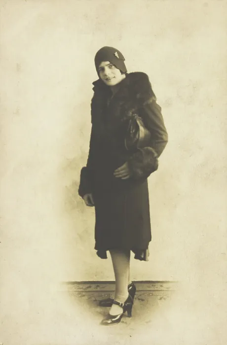 Framed Print : A person poses wearing a long coat with fur trim and a hat with a brooch, [between 1920 and 1929?]. Creator: Unknown