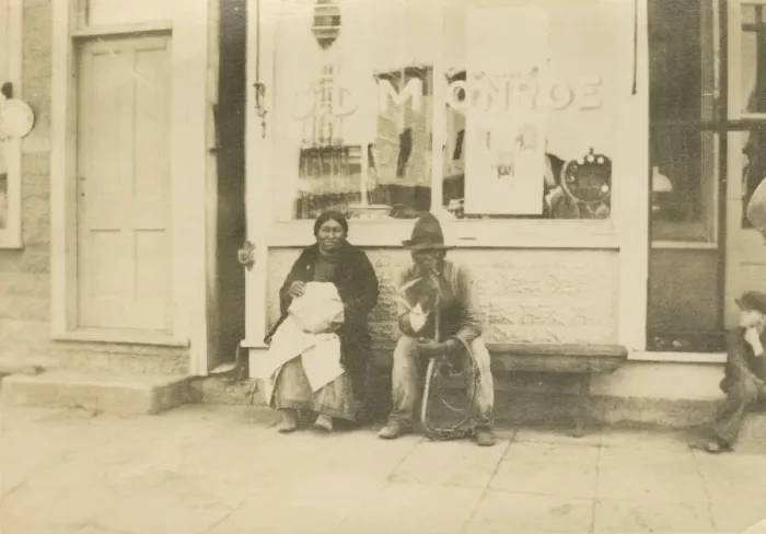 Framed Print : Photograph of a man and woman sitting outside of a storefront, early 20th century Framed Print : Photograph of a man and woman sitting outside of a storefront, early 20th century