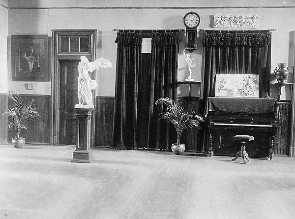 Room with piano, potted palms, and classical statues and friezes, (1899?). Creator: Frances Benjamin Johnston