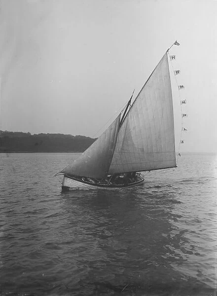 The sailing dinghy Hound with flags, 1912. Creator: Kirk & Sons of Cowes