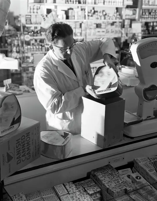 Framed Print : Shopkeeper unpacking canned gammon joints, Mexborough, South Yorkshire, 1963. Artist Framed Print : Shopkeeper unpacking canned gammon joints, Mexborough, South Yorkshire, 1963. Artist