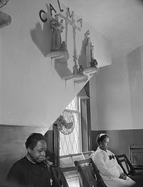 Sitting beneath the emblem of the crucifixion of Jesus on Calvary, Washington, D. C. 1942. Creator: Gordon Parks