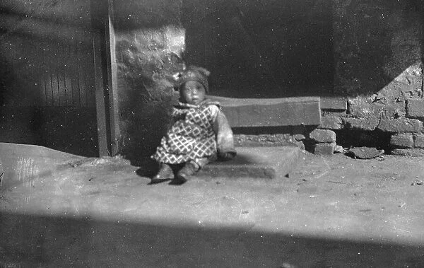 Small child sitting on a doorstep, Chinatown, San Francisco, between 1896 and 1906. Creator: Arnold Genthe