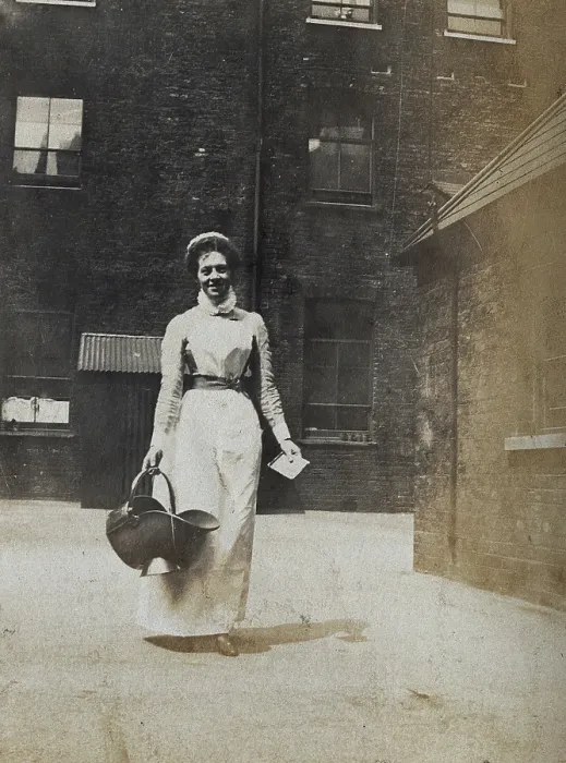 Framed Print : St Bartholomew's Hospital, London: a smiling nurse carrying a coal scuttle, c1890 Framed Print : St Bartholomew's Hospital, London: a smiling nurse carrying a coal scuttle, c1890