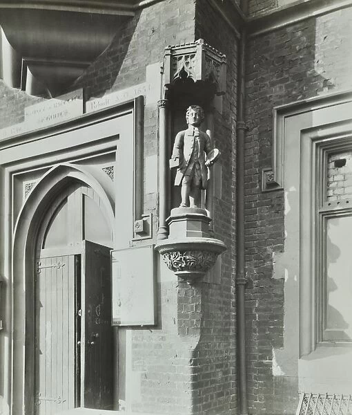 Statue of a boy scholar beside the door, Hamlet of Ratcliff Schools, Stepney, London, 1945
