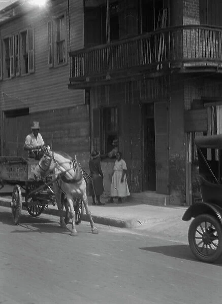 Street scene, including horse- or mule-drawn wagon, New Orleans, between 1920 and 1926. Creator: Arnold Genthe