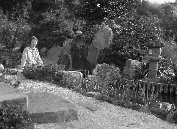 Unidentified woman seated in a garden next to a stream, possibly belonging to A.W. Bahr, c 1917-1934 Creator: Arnold Genthe