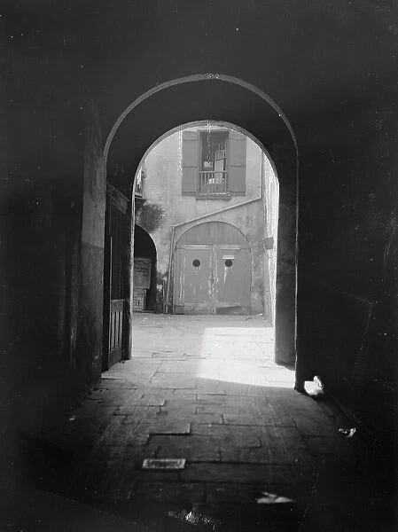 View of a courtyard through an arched passageway, New Orleans, between 1920 and 1926. Creator: Arnold Genthe