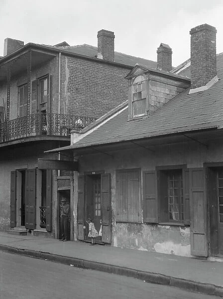 View from across street of two children standing in a doorway in the French Quarter... c1920-1926. Creator: Arnold Genthe