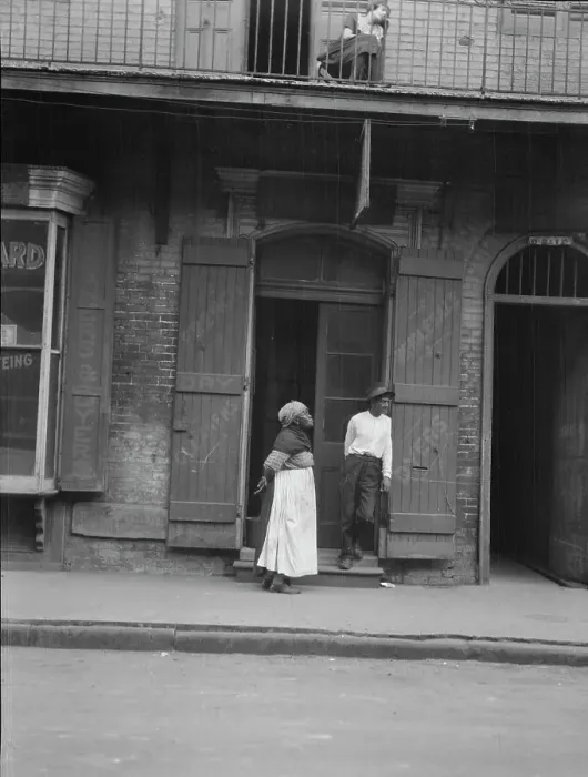 Framed Print : View from across street of a man and woman standing by a doorway and a woman seated...c1920-1926. Creator: Arnold Genthe Framed Print : View from across street of a man and woman standing by a doorway and a woman seated...c1920-1926. Creator: Arnold Genthe