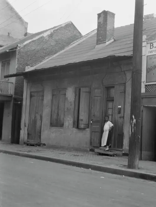 Framed Print : View from across street of a woman standing by a doorway in the French Quarter, New... c1920-c1926. Creator: Arnold Genthe Framed Print : View from across street of a woman standing by a doorway in the French Quarter, New... c1920-c1926. Creator: Arnold Genthe
