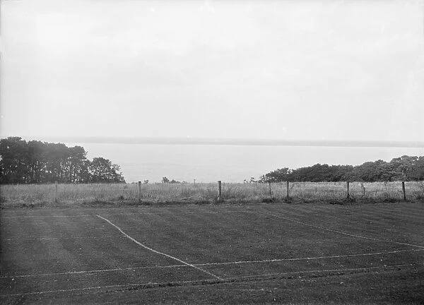 View of a tennis court and the sea, c1935. Creator: Kirk & Sons of Cowes