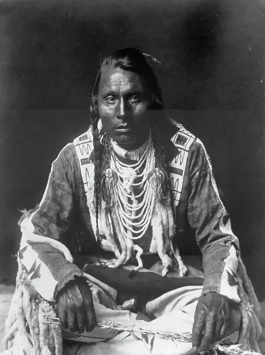 Framed Print : Wades in Water, Piegan Indian, full-length portrait, seated on floor, facing front... c1910. Creator: Edward Sheriff Curtis Framed Print : Wades in Water, Piegan Indian, full-length portrait, seated on floor, facing front... c1910. Creator: Edward Sheriff Curtis