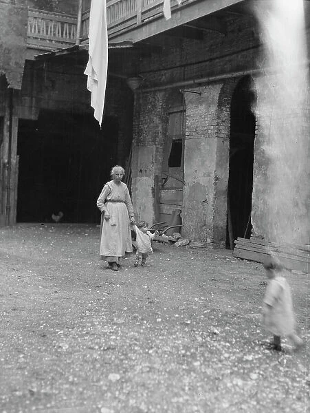Woman and children in a courtyard, New Orleans, between 1920 and 1926. Creator: Arnold Genthe