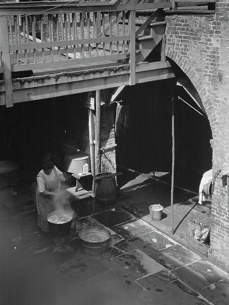 Woman doing laundry in a courtyard, New Orleans, between 1920 and 1926. Creator: Arnold Genthe