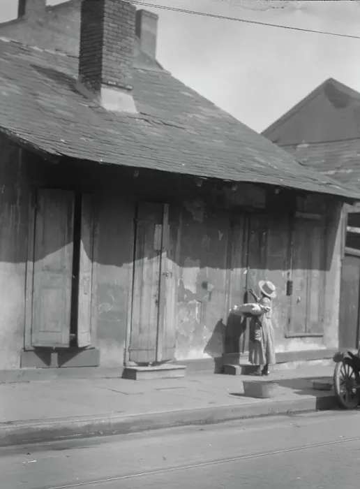 Framed Print : Woman holding a sack standing by the doorway of a building in the French Quarter... c1920-c1926. Creator: Arnold Genthe Framed Print : Woman holding a sack standing by the doorway of a building in the French Quarter... c1920-c1926. Creator: Arnold Genthe
