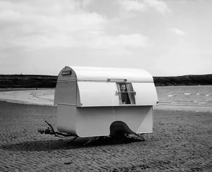 Framed Print : Woman smiling from the window of a trailer caravan on a beach, (c1960s?) Framed Print : Woman smiling from the window of a trailer caravan on a beach, (c1960s?)