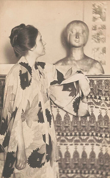 Woman wearing a kimono, standing, looking at a sculpted bust, c1900. Creator: Eva Watson-Schutze