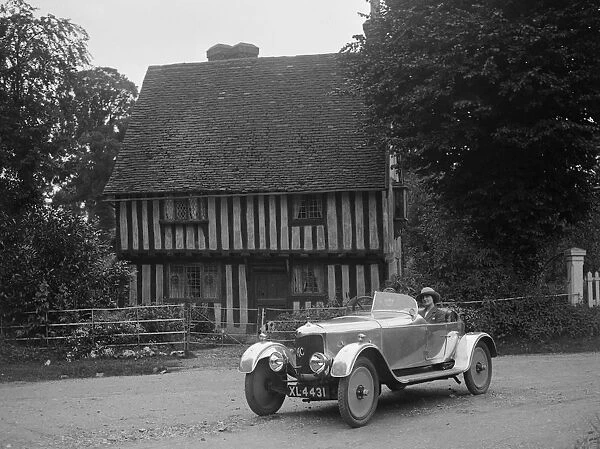 Two women in a AC motor car in front of a Tudor house, c1930s Artist: Bill Brunell