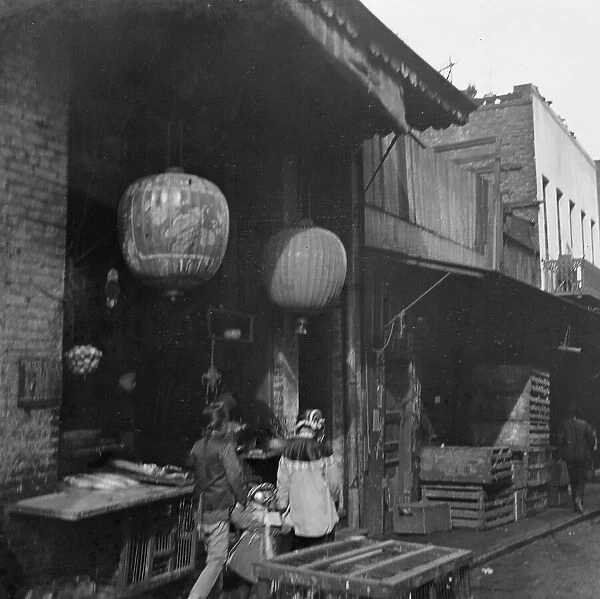 Two women and a child walking down a sidewalk betwen crates, Chinatown, San Francisco, c1896-1906. Creator: Arnold Genthe