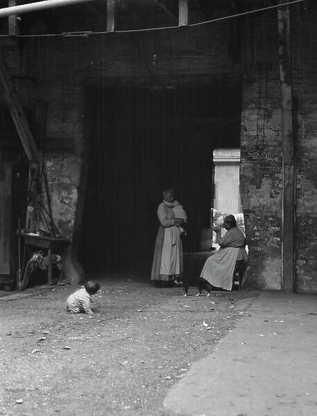 Women and children in a courtyard, New Orleans, between 1920 and 1926. Creator: Arnold Genthe