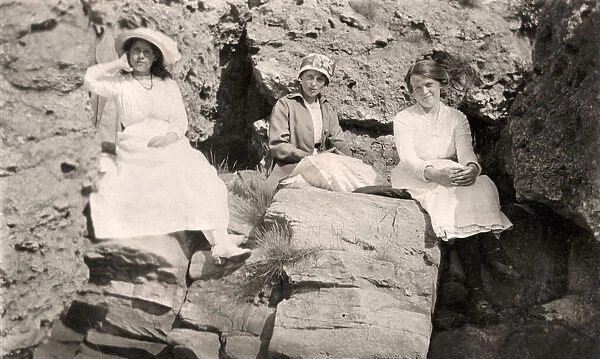 Three women relaxing on rocks, early 20th century