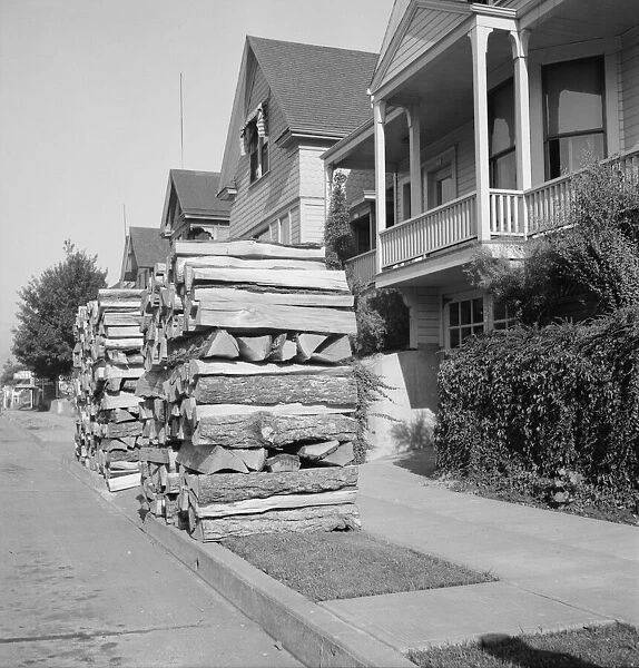 Woodpiles along the street are a characteristic of Portland, Oregon, 1939. Creator: Dorothea Lange