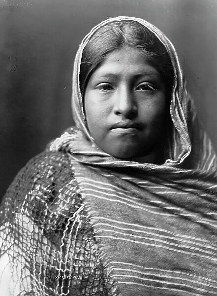 Yaqui girl, head-and-shoulders portrait, facing front, with striped shawl draped around... c1907. Creator: Edward Sheriff Curtis