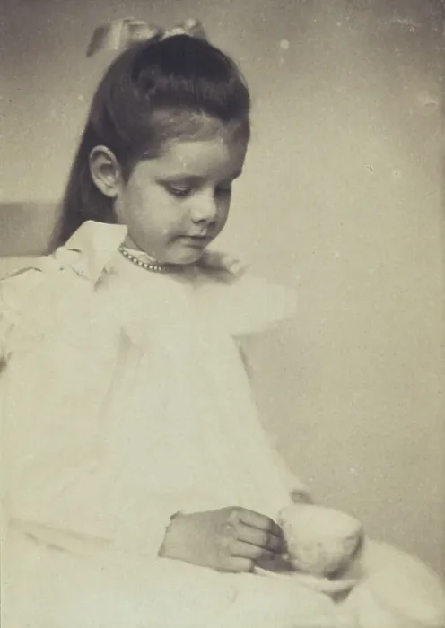 Framed Print : Young girl in white dress, seated holding teacup and saucer, c1900. Creator: Anne K Pilsbury Framed Print : Young girl in white dress, seated holding teacup and saucer, c1900. Creator: Anne K Pilsbury