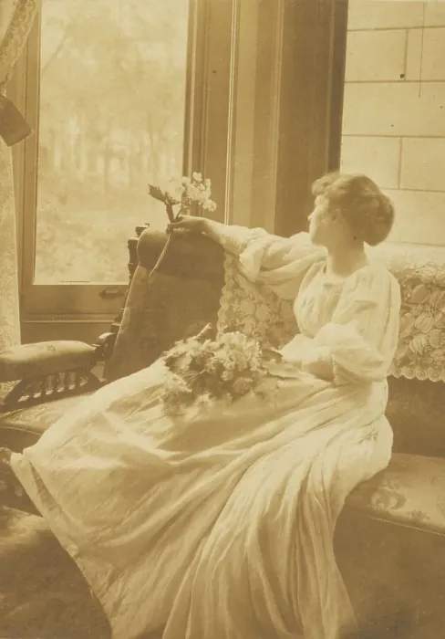 Framed Print : Young woman seated by a window with flowers in her lap, c1900. Creator: Mary A. Bartlett Framed Print : Young woman seated by a window with flowers in her lap, c1900. Creator: Mary A. Bartlett