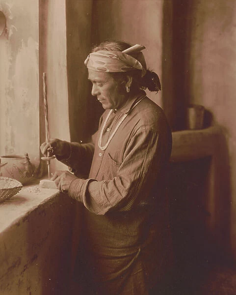 Zuni Indian bead worker drilling holes in beads, c1903. Creator: Edward Sheriff Curtis