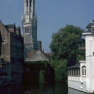 Canal, old houses, and the Belfrey of the Tour Des Halles in Bruges